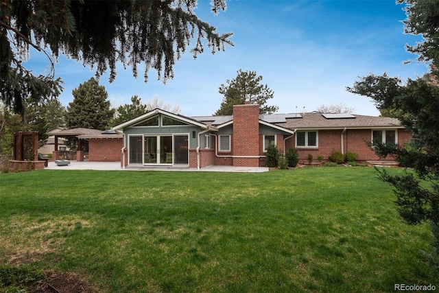5164 E Princeton Ave, Cherry Hills Village, CO 80113 - rear view of house featuring brick siding, roof mounted solar panels, a chimney, and a patio