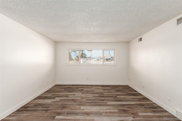 spare room featuring dark hardwood / wood-style floors and a textured ceiling