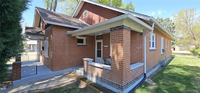 view of side of home with brick siding, a yard, and roof with shingles