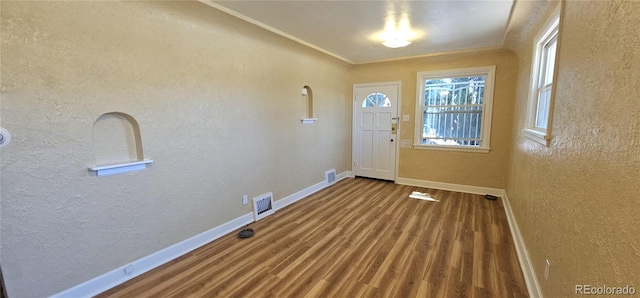 entryway featuring baseboards, wood finished floors, and a textured wall