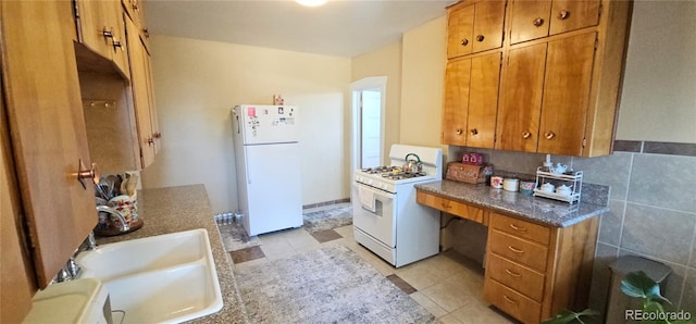 kitchen featuring white appliances, brown cabinets, and a sink