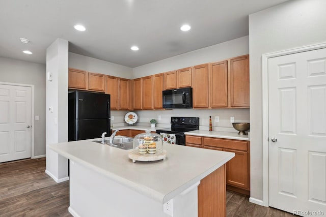 kitchen with recessed lighting, light countertops, black appliances, and a center island with sink