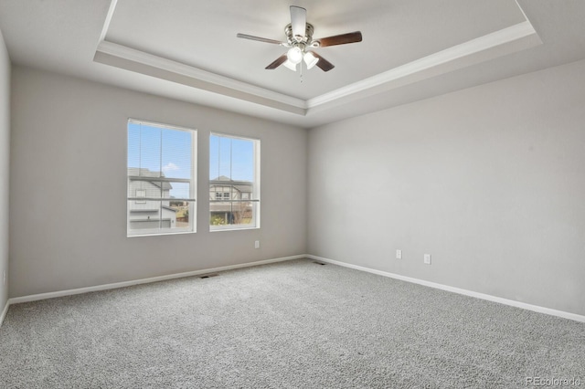empty room featuring crown molding, a ceiling fan, carpet flooring, and a raised ceiling
