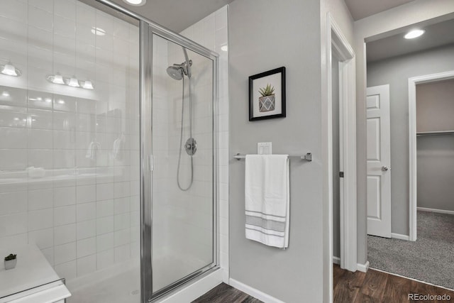 bathroom featuring baseboards, a shower stall, and wood finished floors