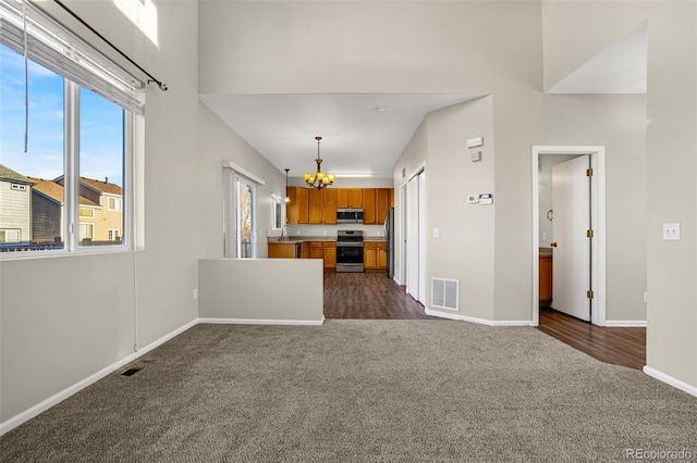 kitchen featuring brown cabinetry, visible vents, appliances with stainless steel finishes, open floor plan, and dark carpet