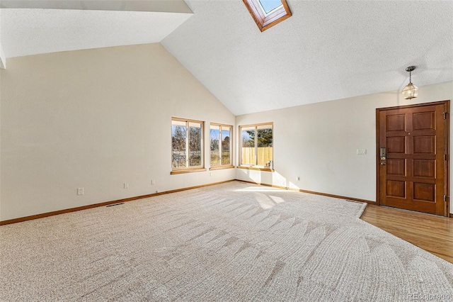 unfurnished living room with lofted ceiling with skylight and carpet flooring