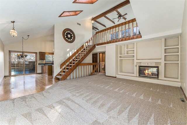 unfurnished living room with ceiling fan, carpet flooring, built in features, and high vaulted ceiling