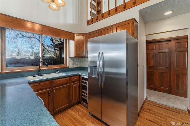 kitchen featuring wine cooler, backsplash, sink, light wood-type flooring, and stainless steel fridge with ice dispenser