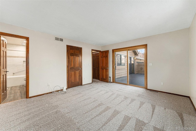 unfurnished bedroom with light colored carpet, access to exterior, and connected bathroom