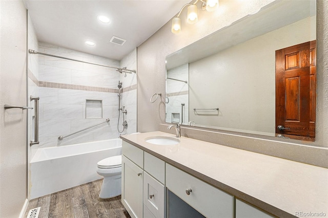 full bathroom with toilet, tiled shower / bath combo, hardwood / wood-style flooring, and vanity