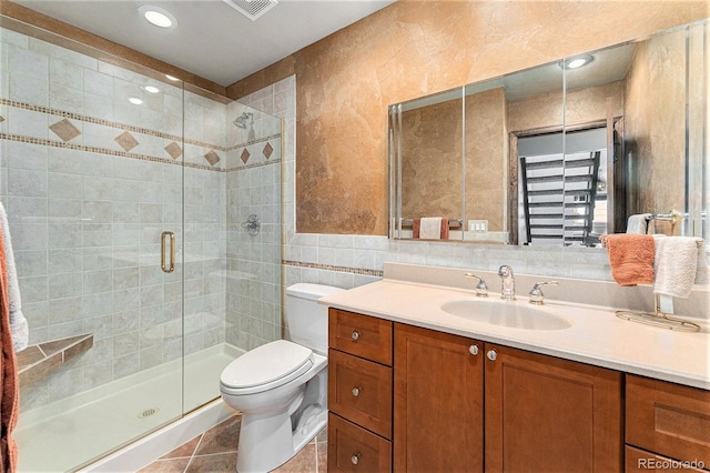 bathroom with toilet, tile walls, tile patterned floors, an enclosed shower, and vanity