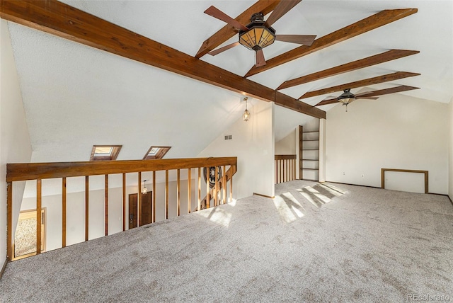 carpeted spare room featuring ceiling fan and vaulted ceiling with beams