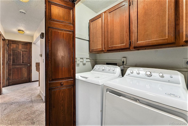 laundry area with a textured ceiling, cabinets, carpet flooring, and washer and clothes dryer