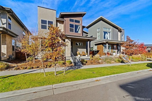 contemporary house featuring a front lawn and covered porch