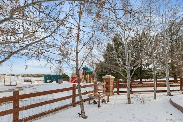 yard covered in snow featuring a playground and fence