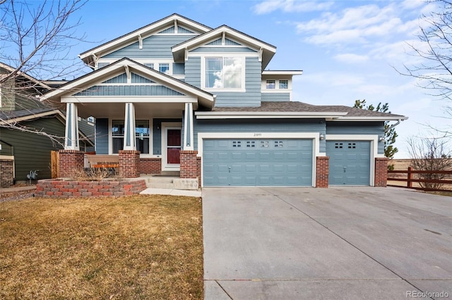 craftsman house featuring brick siding, covered porch, concrete driveway, fence, and a front lawn