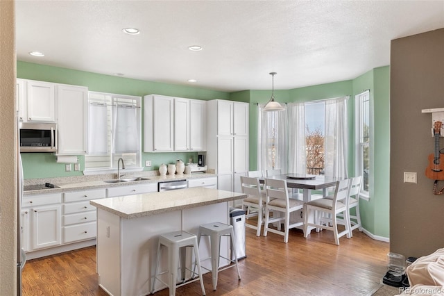 kitchen with white cabinetry, wood finished floors, appliances with stainless steel finishes, and a sink