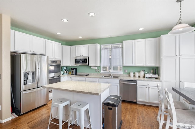 kitchen with a kitchen bar, light wood-style floors, white cabinets, stainless steel appliances, and a sink