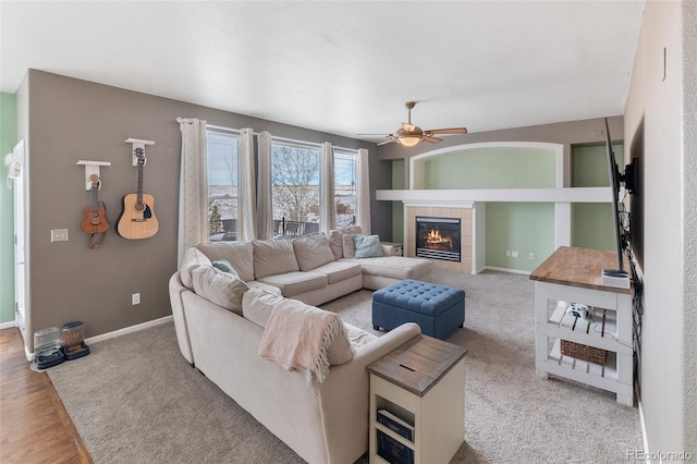 living room featuring ceiling fan, baseboards, and a tile fireplace