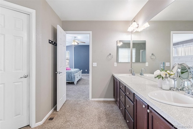 bathroom with a sink, connected bathroom, baseboards, and double vanity