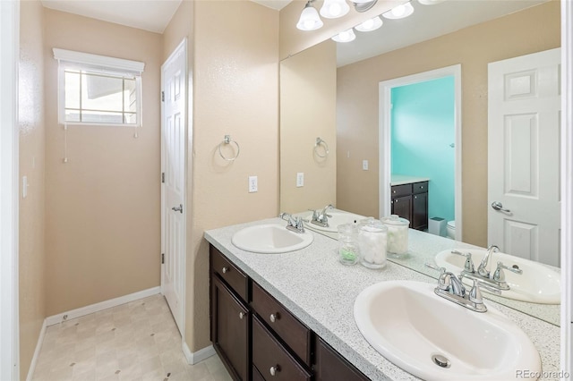 bathroom with double vanity, toilet, and a sink