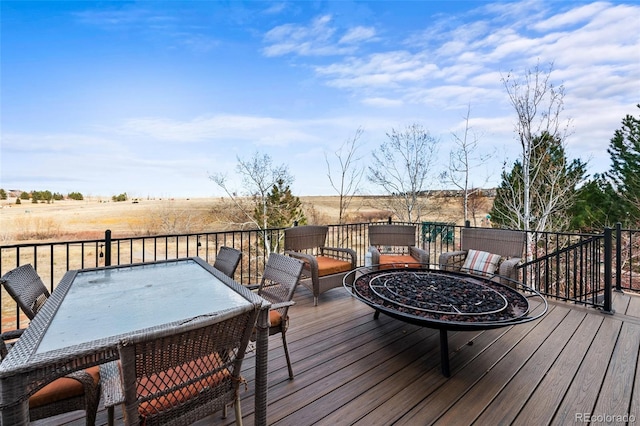 deck with outdoor dining space and an outdoor fire pit