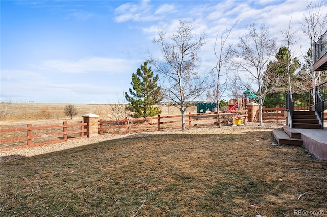 view of yard with a rural view, a playground, and fence