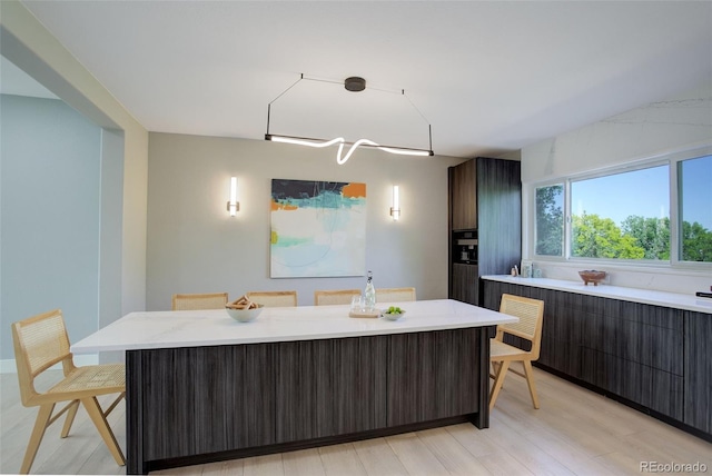 7400 S Genoa Cir, Centennial, CO 80016 - kitchen featuring a kitchen island, modern cabinets, black oven, light wood finished floors, and a breakfast bar area
