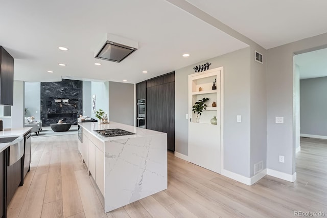 7400 S Genoa Cir, Centennial, CO 80016 - kitchen with modern cabinets, appliances with stainless steel finishes, light wood-style flooring, a center island, and light stone counters