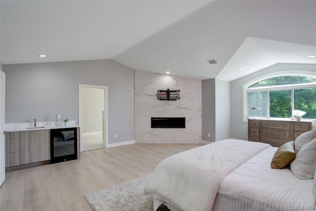 7400 S Genoa Cir, Centennial, CO 80016 - bedroom featuring lofted ceiling, beverage cooler, a fireplace, light wood-style flooring, and recessed lighting