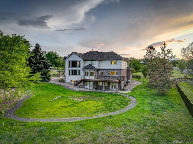 7400 S Genoa Cir, Centennial, CO 80016 - back of house at dusk featuring stairway, a deck, a yard, a patio area, and stone siding