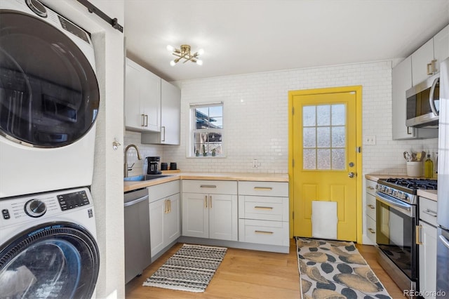 laundry room with sink, stacked washer and dryer, and light wood-type flooring