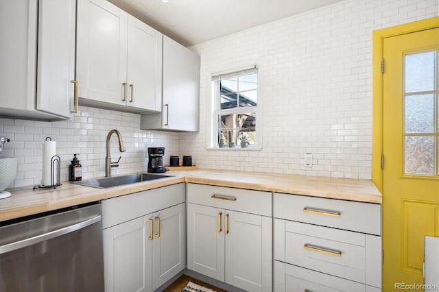 kitchen with sink, butcher block counters, a healthy amount of sunlight, decorative backsplash, and stainless steel dishwasher