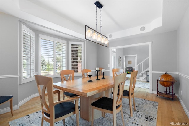 920 Shady Oak Ln, Castle Pines, CO 80108 - dining space featuring a tray ceiling, light wood-style flooring, stairway, and baseboards