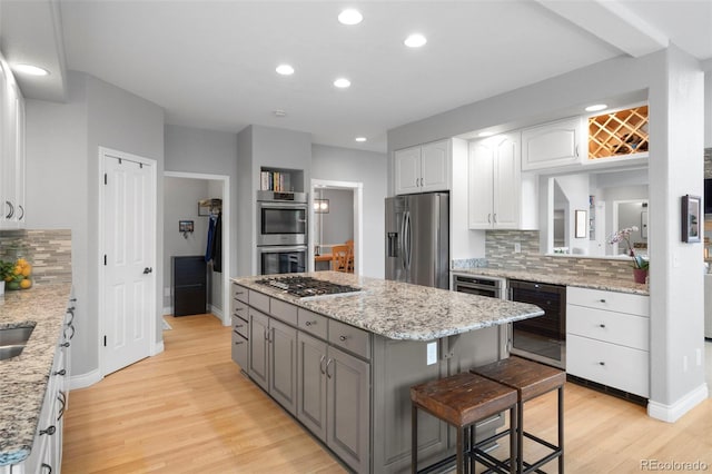 920 Shady Oak Ln, Castle Pines, CO 80108 - kitchen with stainless steel appliances, a kitchen island, white cabinets, light wood-style flooring, and backsplash