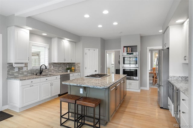 920 Shady Oak Ln, Castle Pines, CO 80108 - kitchen featuring appliances with stainless steel finishes, a sink, a center island, light wood finished floors, and tasteful backsplash