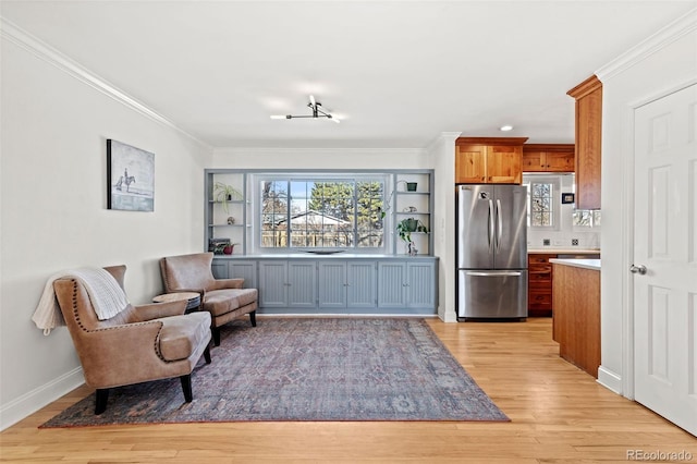 sitting room featuring crown molding, built in features, and light wood-type flooring