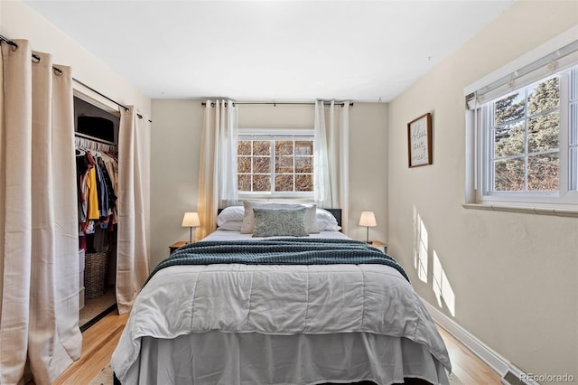 bedroom with a closet, multiple windows, and light wood-type flooring