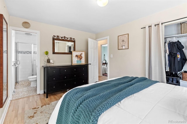 bedroom featuring ensuite bath, light wood-type flooring, and a closet