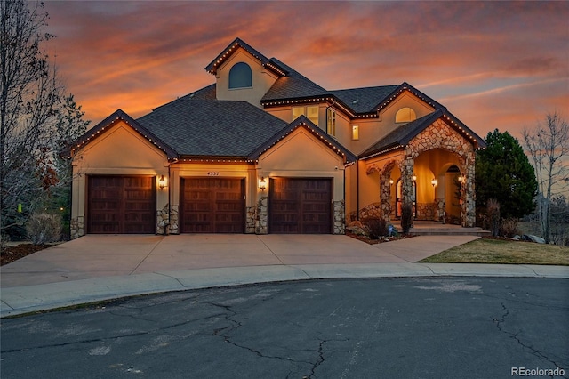 view of front of home featuring stone siding, concrete driveway, an attached garage, and stucco siding