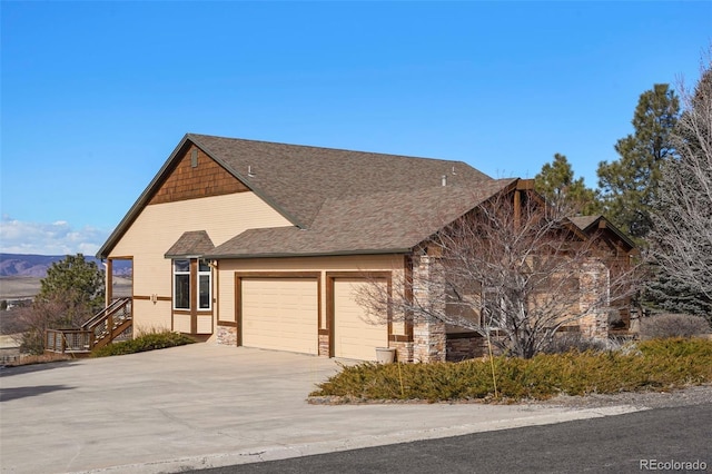 view of front facade with concrete driveway, stone siding, an attached garage, and a shingled roof