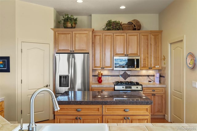 kitchen with tile countertops, recessed lighting, stainless steel appliances, a sink, and tasteful backsplash