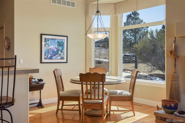 dining space with baseboards, visible vents, and wood finished floors