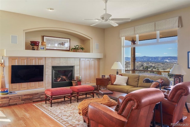 living room featuring visible vents, a tiled fireplace, a mountain view, ceiling fan, and wood finished floors