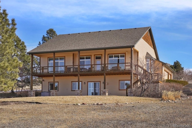 back of house with a balcony and roof with shingles