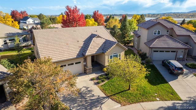 view of front facade with a tiled roof, stone siding, driveway, and an attached garage