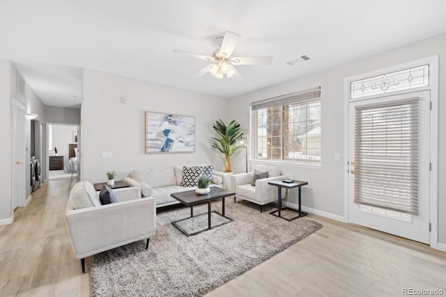 living room with a ceiling fan, light wood-type flooring, visible vents, and baseboards