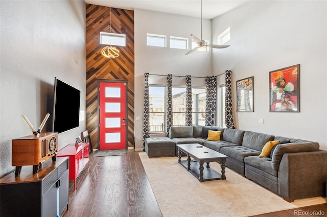 living room featuring ceiling fan, dark hardwood / wood-style flooring, and a towering ceiling