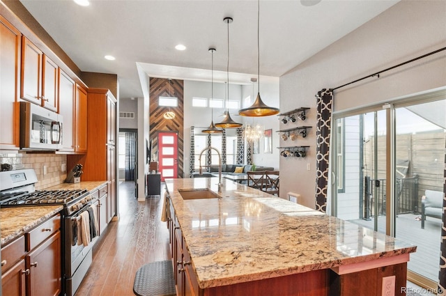 kitchen featuring a wealth of natural light, appliances with stainless steel finishes, a kitchen island with sink, sink, and pendant lighting