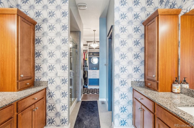 bathroom with walk in shower, vanity, and tile patterned flooring